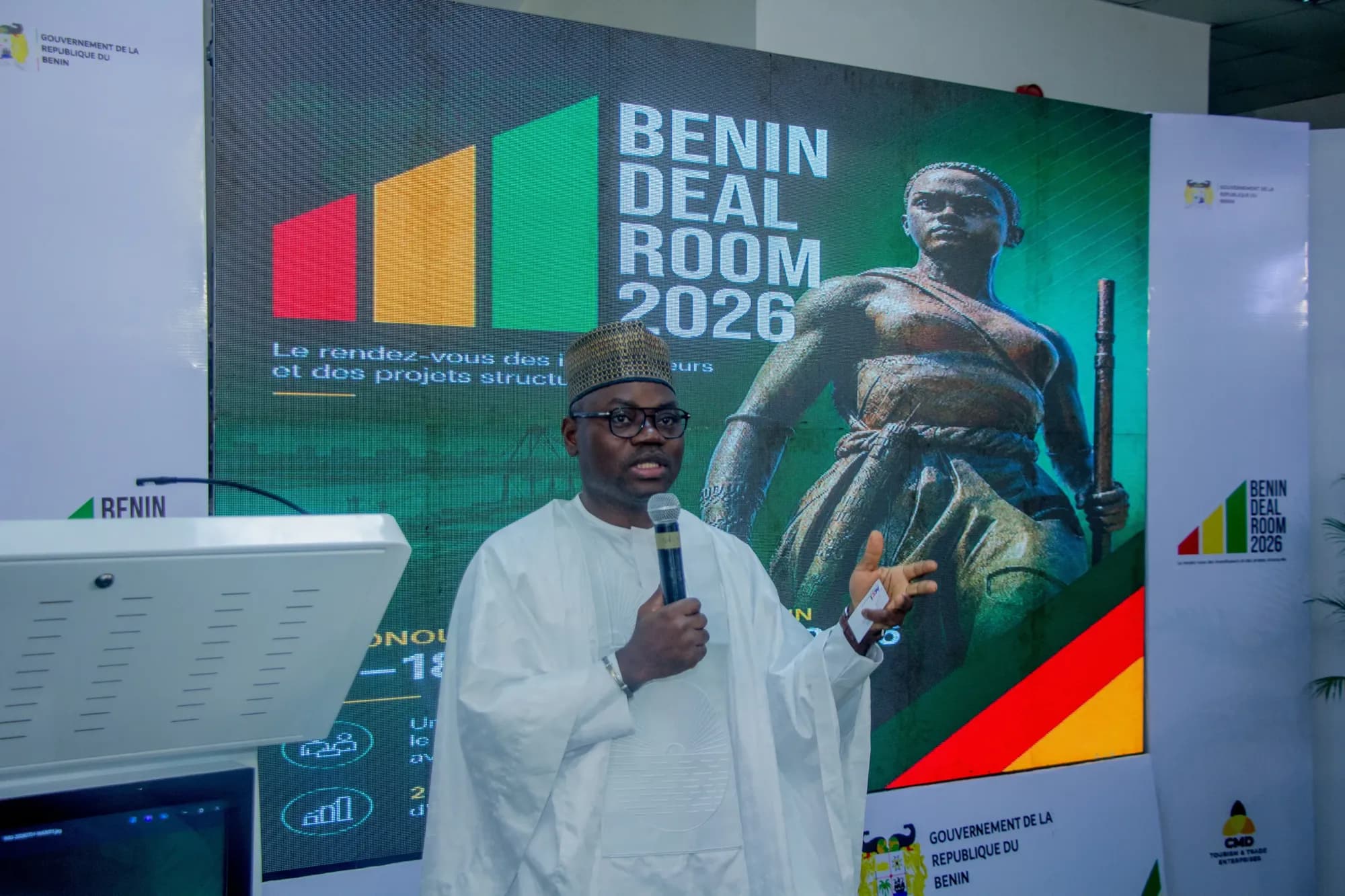 A speaker addresses delegates beneath the Benin Deal Room 2026 backdrop